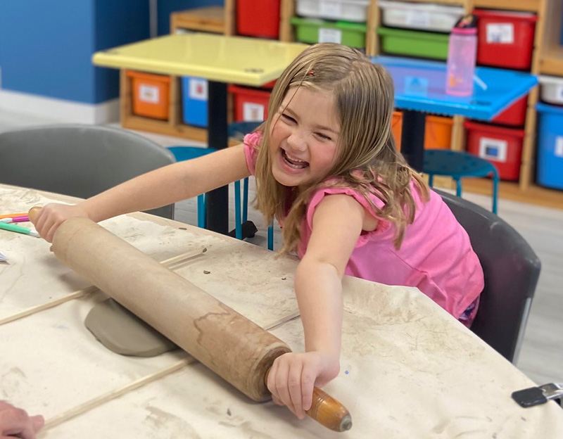smiling creative student hands on learning with rolling pin